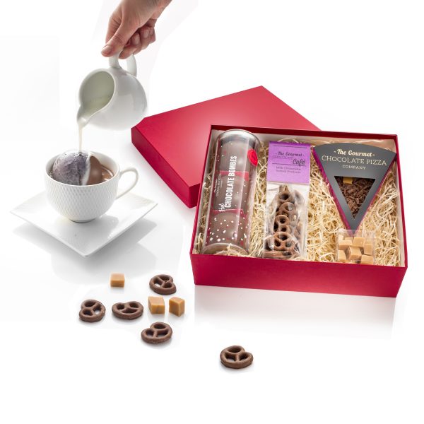 chocolate gift box with chocolate bombe in a mug and pouring milk over.